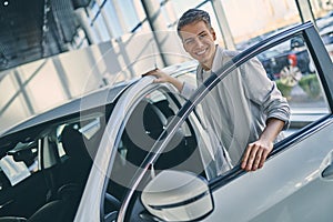 Happy man rejoicing buying a new car in showroom