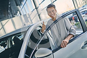 Happy man rejoicing buying a new car in showroom