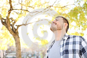 Happy man relaxing breathing deep fresh air in a park