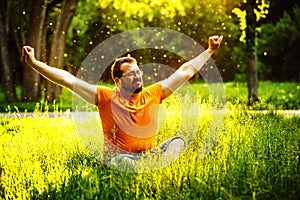 A happy man is relaxing on green grass with squint eyes