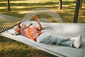Happy man relaxing in hammock with tablet