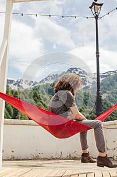 Happy man relaxing lying in hammock on top of mountain. Summer vacation travel lifestyle concept