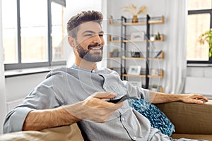 happy man with remote control watching tv at home