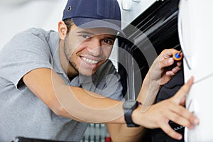 happy man repairing domestic oven in kitchen