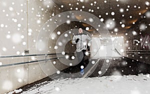 Happy man running along subway tunnel in winter