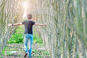 Happy man running on a forest path opposite the sun. hands touching a tree branch