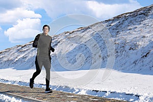 Happy man running past snowy hill in winter.