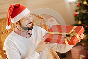 Happy man scrutinizing gift box in his hands