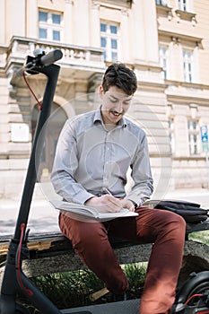 Happy man in shirt writing in notebook outdoor