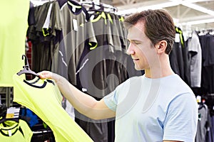 Happy man shopping for sport t-shirt in shop