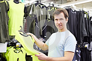 Happy man shopping for sport t-shirt in shop