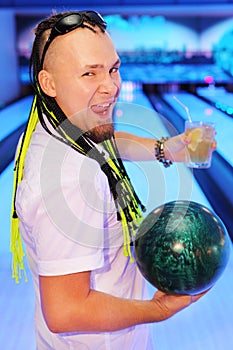 Happy man shouts, holds ball and glass in bowling