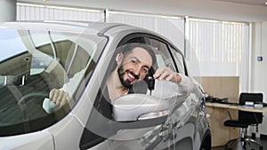 Happy man showing the key of his new car. Auto business, car sale, technology and people concept - happy male with car