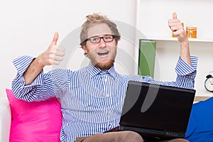 Happy man shows OK sign in front of a computer