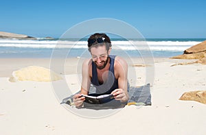 Happy man sitting on the beach reading a book