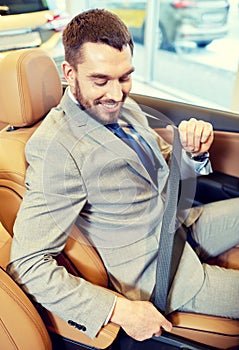 Happy man sitting in car at auto show or salon