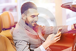 Happy man sitting in car at auto show or salon