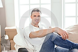 Happy man sitting on the couch in his new apartment