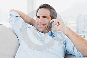 Happy man sitting on the couch on the phone