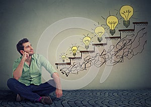 Happy man sitting on a floor in his office dreaming of business education success