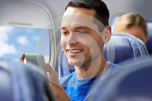 Happy man sitting in plane with smartphone