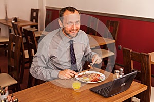 Happy man sitting in restaurant with laptop