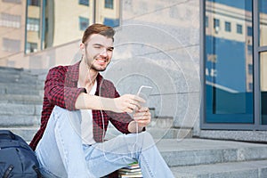 Happy man sitting on the steps listening to music outdoors