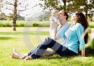 Happy man sitting with wife and kissing little son