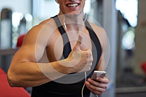 Happy man with smartphone and earphones in gym