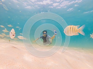 Happy man in snorkeling mask dive underwater with tropical fishes with thailand flag in coral reef sea pool. Travel