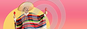 Happy man in sombrero and bright poncho isolated over red yellow background