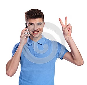 Happy man speaking on the phone makes the victory sign