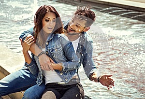 Happy man splashing the water on her girlfriend. Happy young couple in love