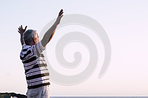 Happy of man standing alone with arms raised up during beautiful sunrise at the sunset. Enjoying with nature - retired man feels