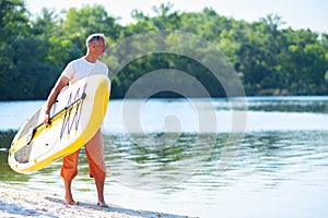 Happy man is standing with a SUP board