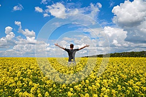 Happy man stands in a yellow field rejoicing raises his hands to the sky