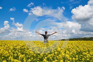 Happy man stands in a yellow field rejoicing raises his hands to the sky