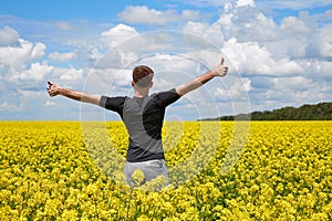 Happy man stands in a yellow field rejoicing raises his hands to the sky