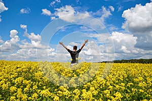 Happy man stands in a yellow field rejoicing raises his hands to the sky