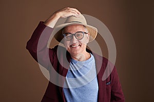 Happy man in straw hat putting one hand on it and smiling