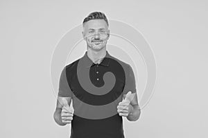 Happy man with stylish beard hair in red tshirt show thumbs ups satisfactory hand gesture yellow background