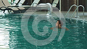 Happy man swimming at modern hotel on vacation. Handsome man bathing at pool.