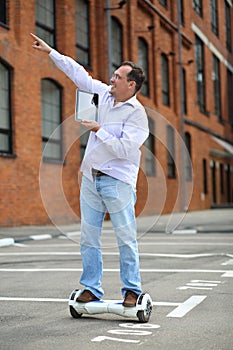 Happy man with tablet points up on GyroScooter photo