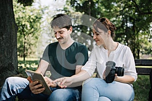 Happy man with tablet sitting on bench with girl