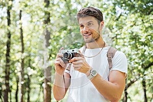 Happy man taking pictures with old photo camera in forest