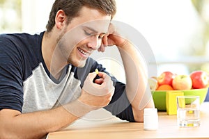 Happy man taking a vitamin pill at home photo