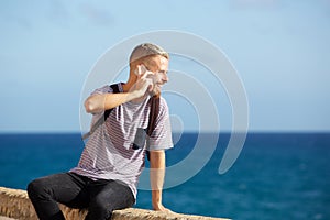 Happy man talking on cell phone by the sea