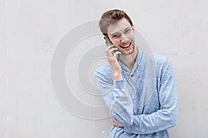Happy man talking with cellphone by wall