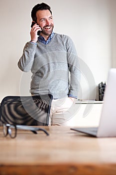 Happy man talking on mobile phone in business office