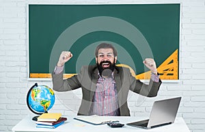 Happy man teacher on laptop screen watching online course, modern workplace